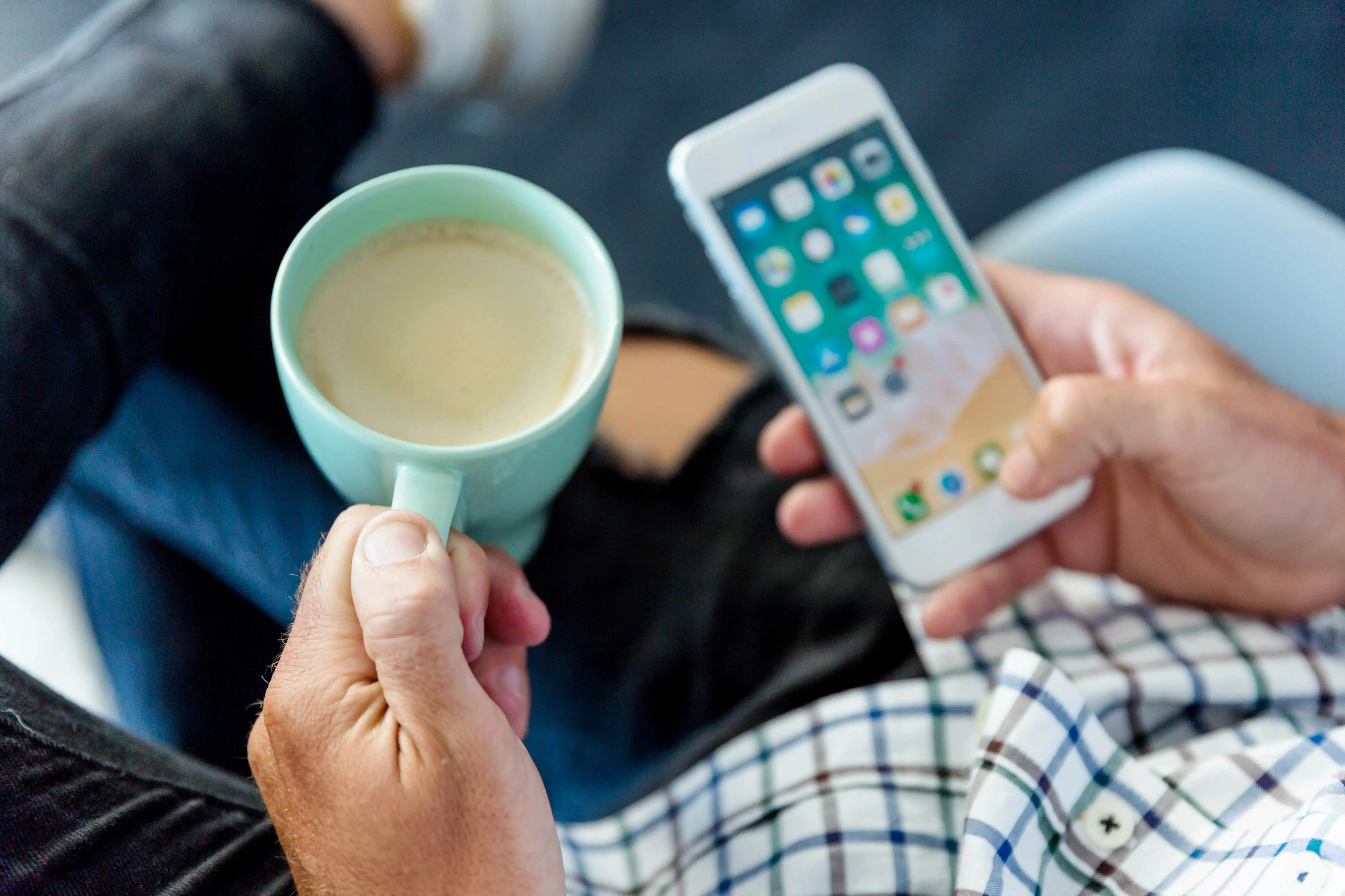 Image d'une personne avec un cafe et un smartphone dans l'autre main